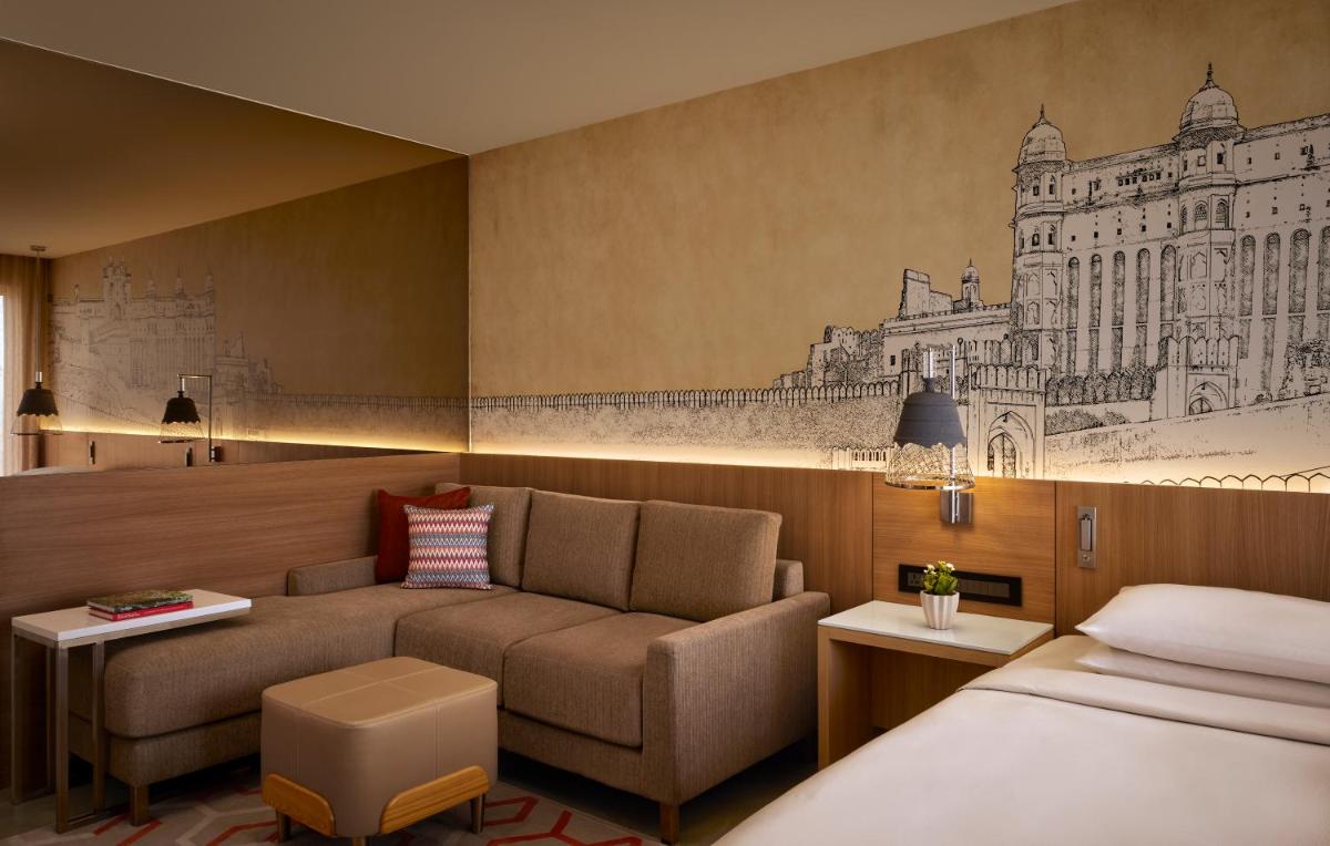 a hotel room with a couch and a bed at Hyatt Place Jaipur Malviya Nagar in Jaipur a hotel room with a couch and a bed at Hyatt Place Jaipur Malviya Nagar in Jaipur