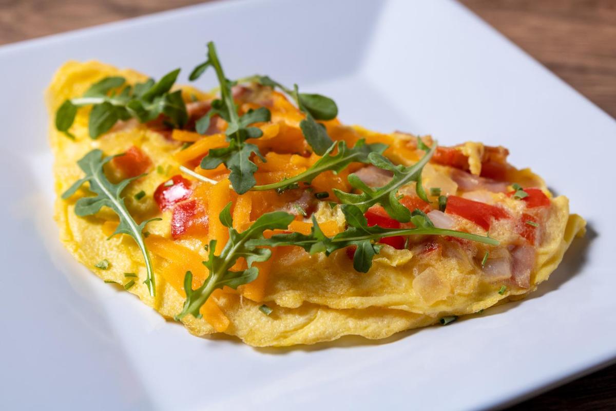 a white plate topped with an omelet with vegetables at Hyatt Place Jaipur Malviya Nagar in Jaipur a white plate topped with an omelet with vegetables at Hyatt Place Jaipur Malviya Nagar in Jaipur