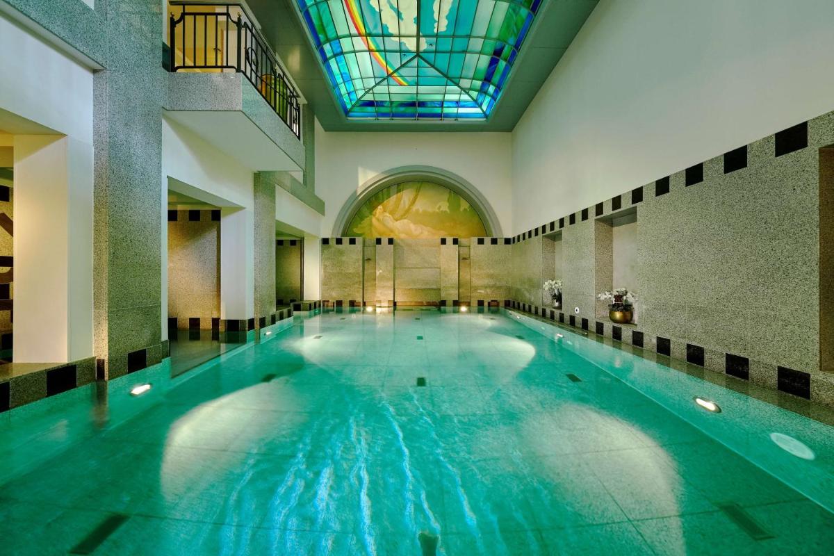 ein großes Schwimmbecken mit einer Buntglasdecke in der Unterkunft Maison Messmer - ein Mitglied der Hommage Luxury Hotels Collection in Baden-Baden
