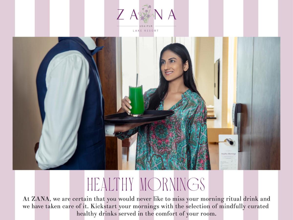 a woman holding a tray with a suit and a drink at ZANA Lakeview Resort - most scenic lakeside resort in Udaipur