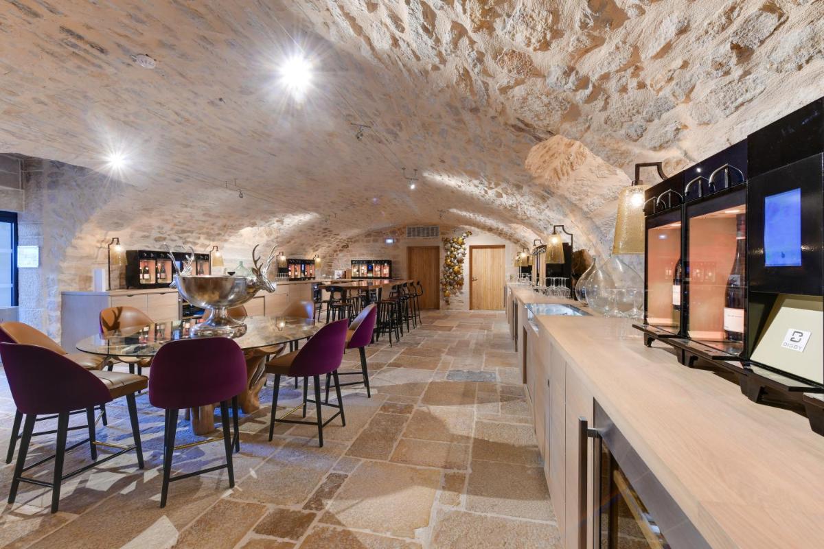 un restaurant avec des murs en pierre, des tables et des chaises violettes dans l'établissement Hôtel & Spa Les Sept Fontaines Best Western Premier, à Tournus