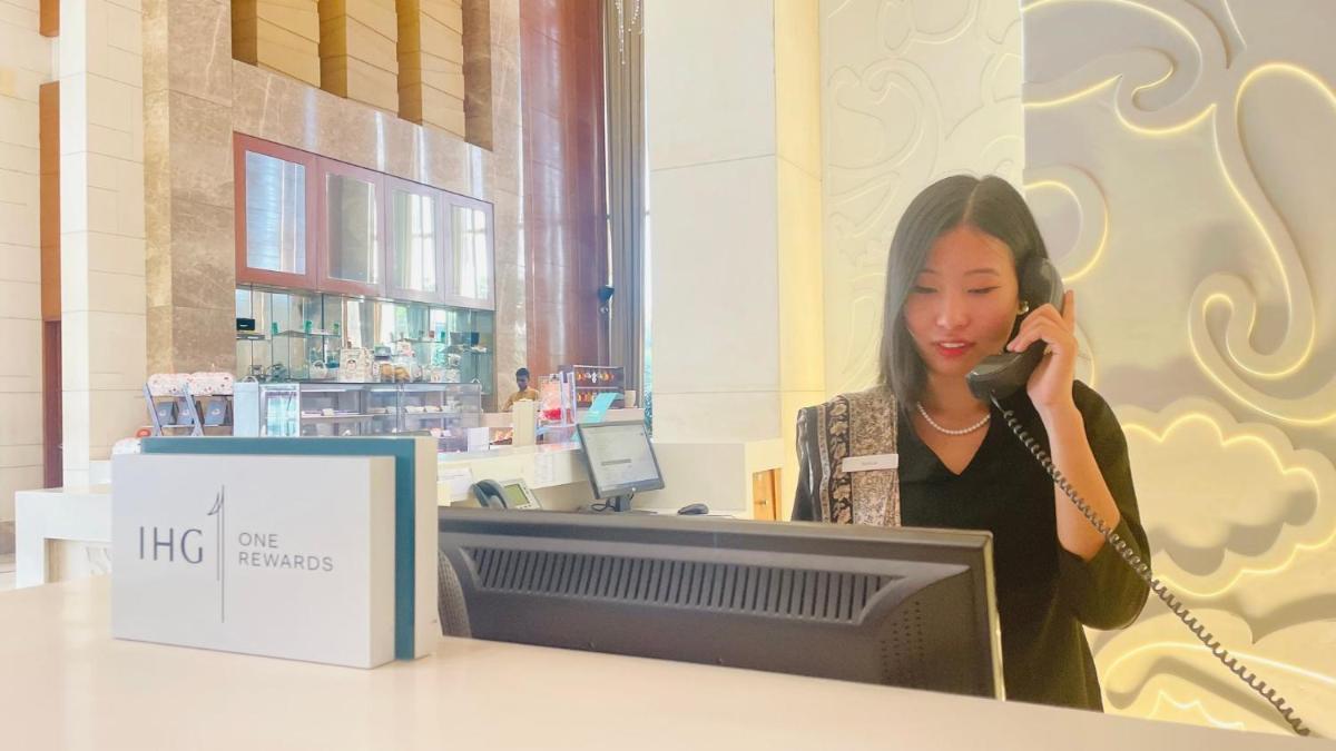 a woman talking on a cell phone next to a computer at Crowne Plaza New Delhi Okhla by IHG in New Delhi