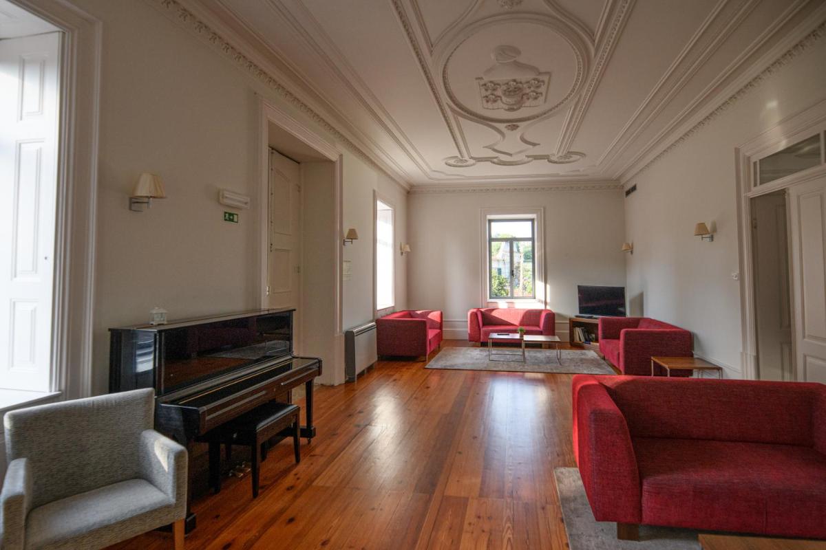 uma sala de estar com um piano e cadeiras vermelhas em Hotel Quinta da Cruz & SPA em Ataíde