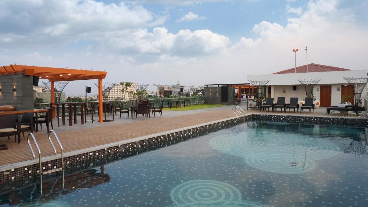 a swimming pool with a wooden deck next to a building at Hyatt Place Hyderabad Banjara Hills in Hyderabad