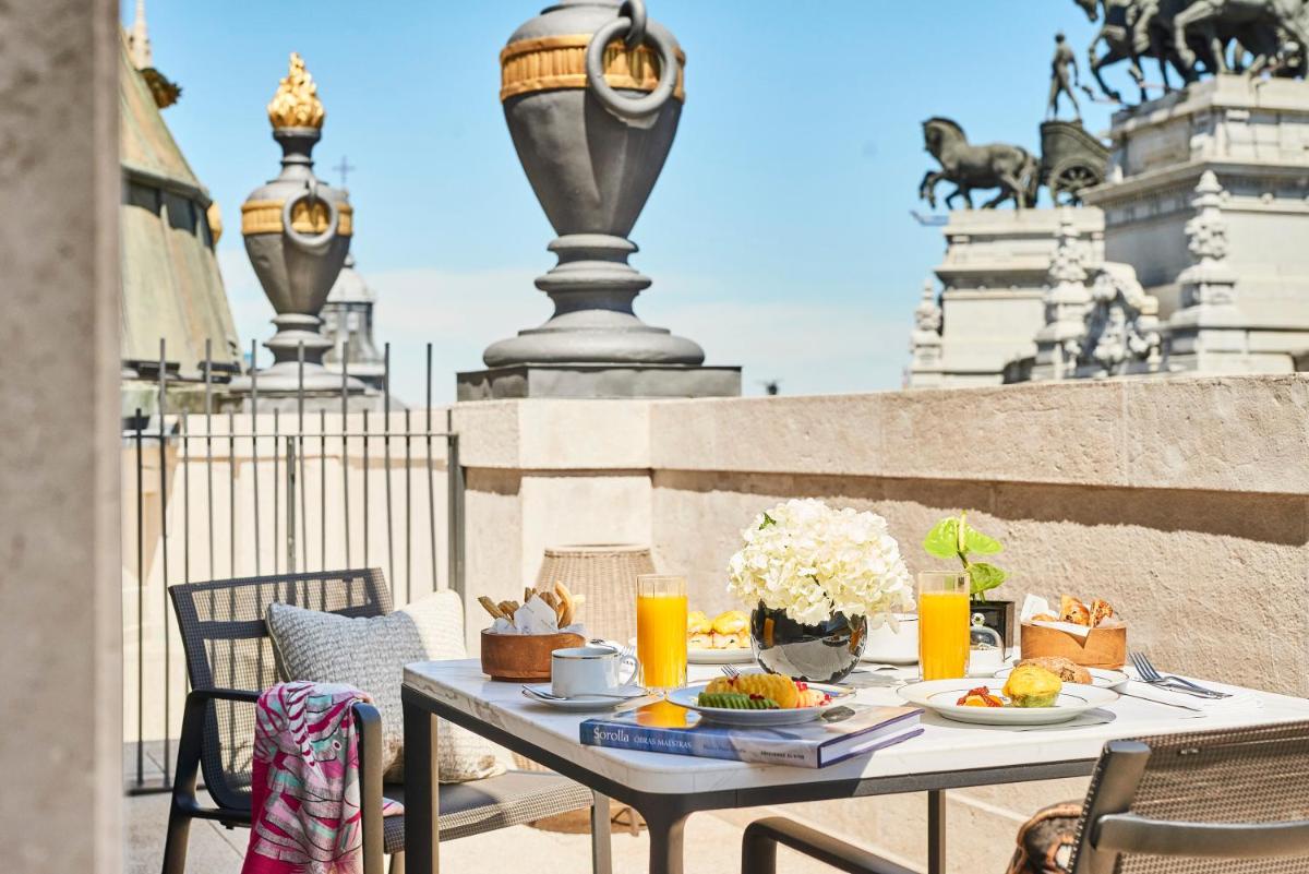 Una mesa con comida y bebidas en un balcón. en Four Seasons Hotel Madrid, en Madrid