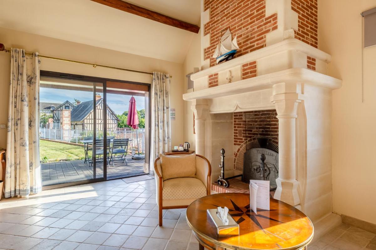 un salon avec une cheminée et une table dans l'établissement Demeures & Châteaux Hôtel Domaine le Clos des Fontaines, à Jumièges