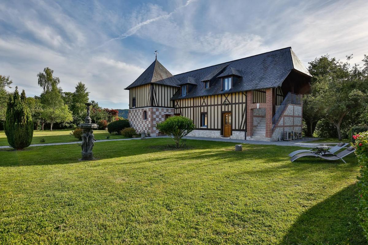 une grande maison avec une grande cour avec de l'herbe dans l'établissement Demeures & Châteaux Hôtel Domaine le Clos des Fontaines, à Jumièges