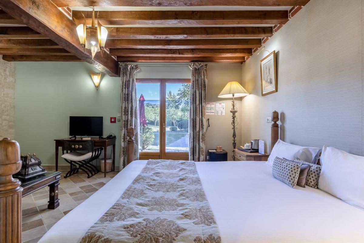 une chambre avec un lit, un bureau et une télévision dans l'établissement Demeures & Châteaux Hôtel Domaine le Clos des Fontaines, à Jumièges