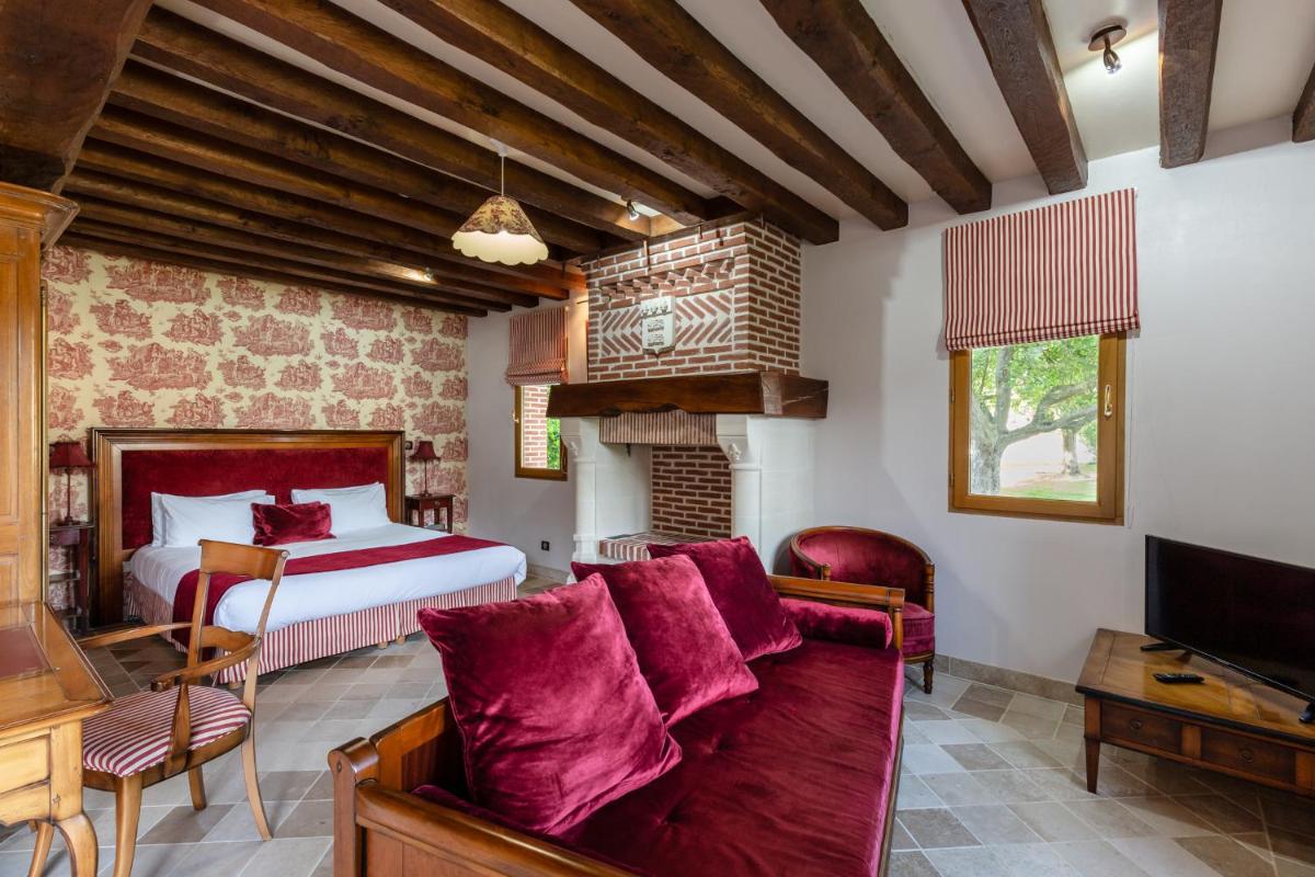 une chambre avec un lit, un canapé et une télévision dans l'établissement Demeures & Châteaux Hôtel Domaine le Clos des Fontaines, à Jumièges