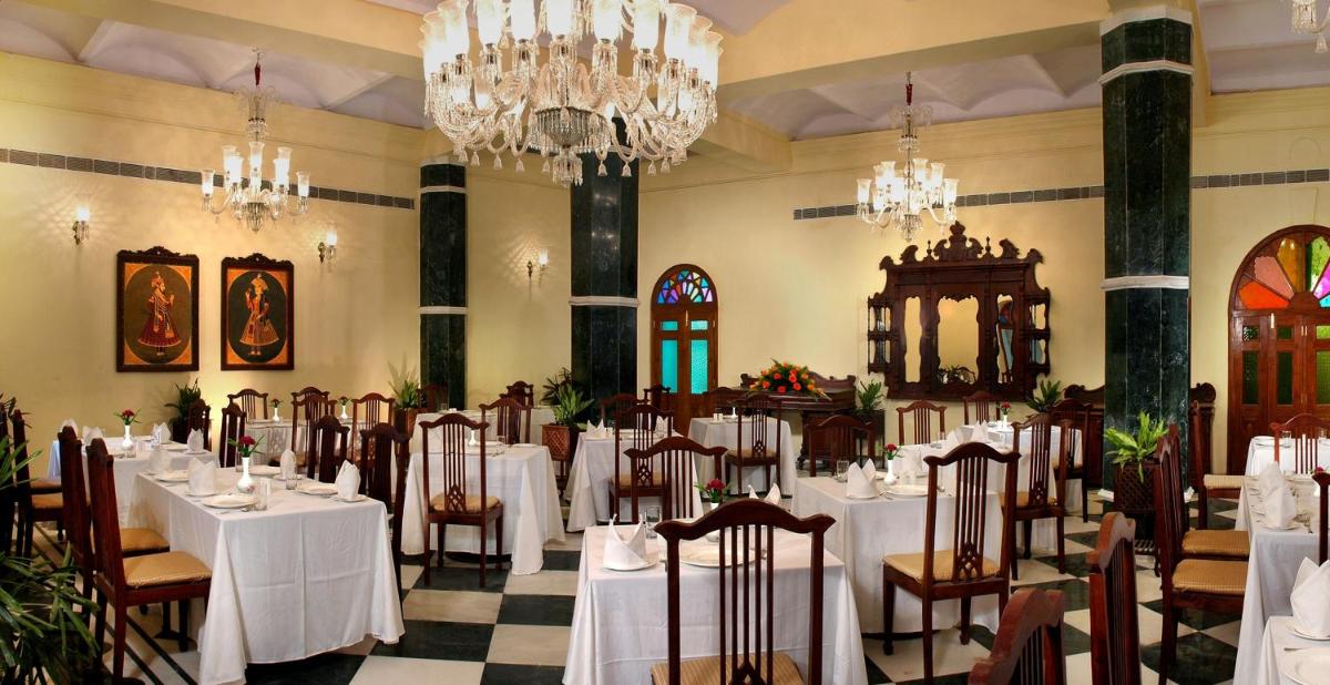 a dining room with white tables and chairs and chandeliers at The Grand Imperial - Heritage Hotel in Agra