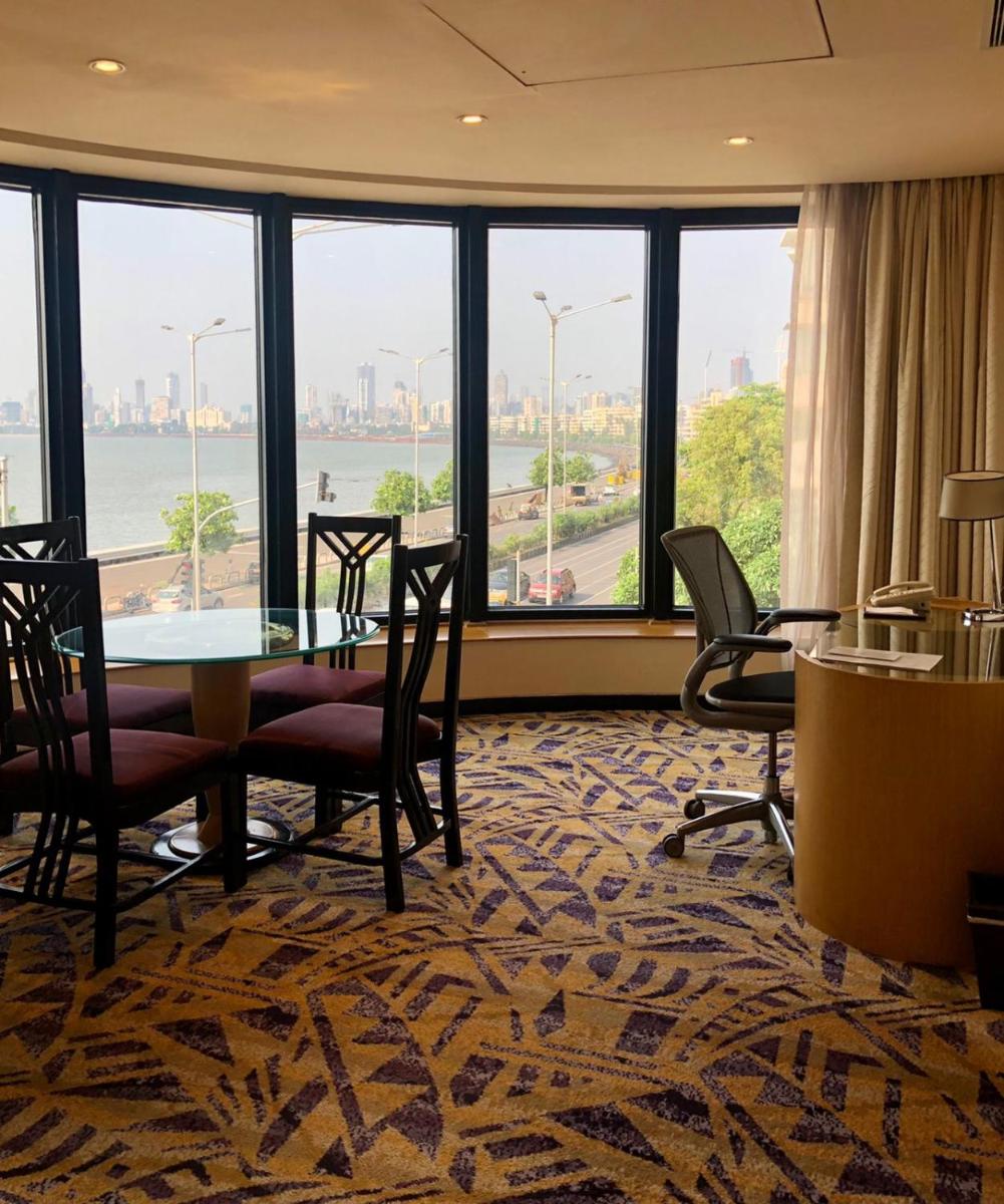 a room with a table and chairs and a large window at Hotel Marine Plaza in Mumbai