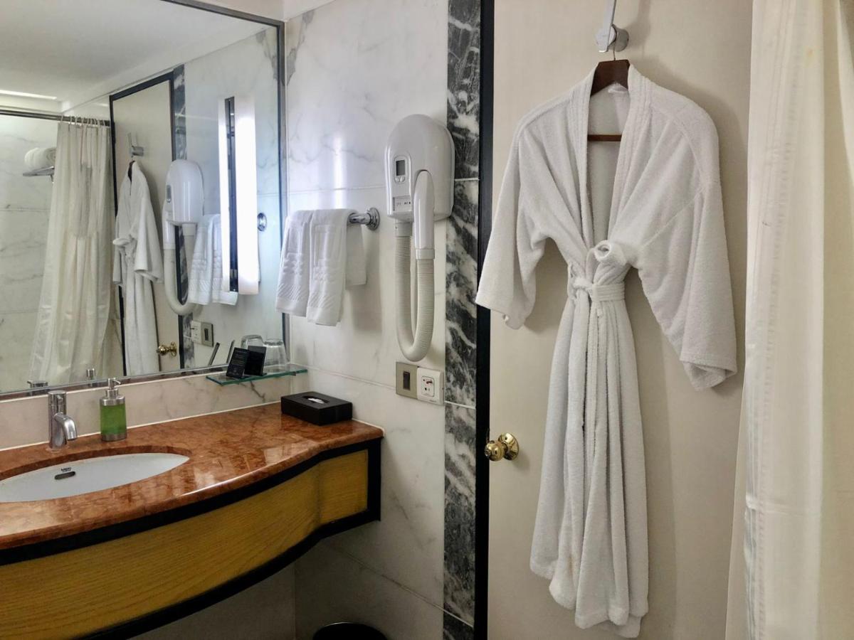 a bathroom with a white robe hanging on a wall at Hotel Marine Plaza in Mumbai