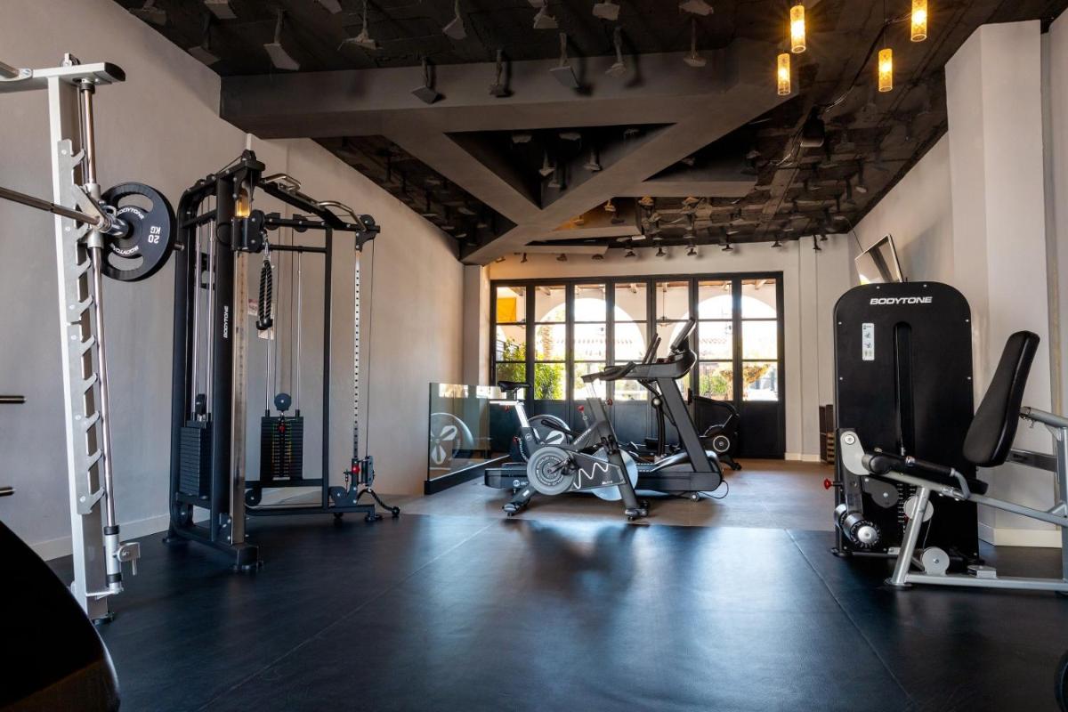 Un gimnasio con varias cintas de correr y máquinas en una sala. en Portomar Apartments - 4-Star Superior Hotel, en Portocolom