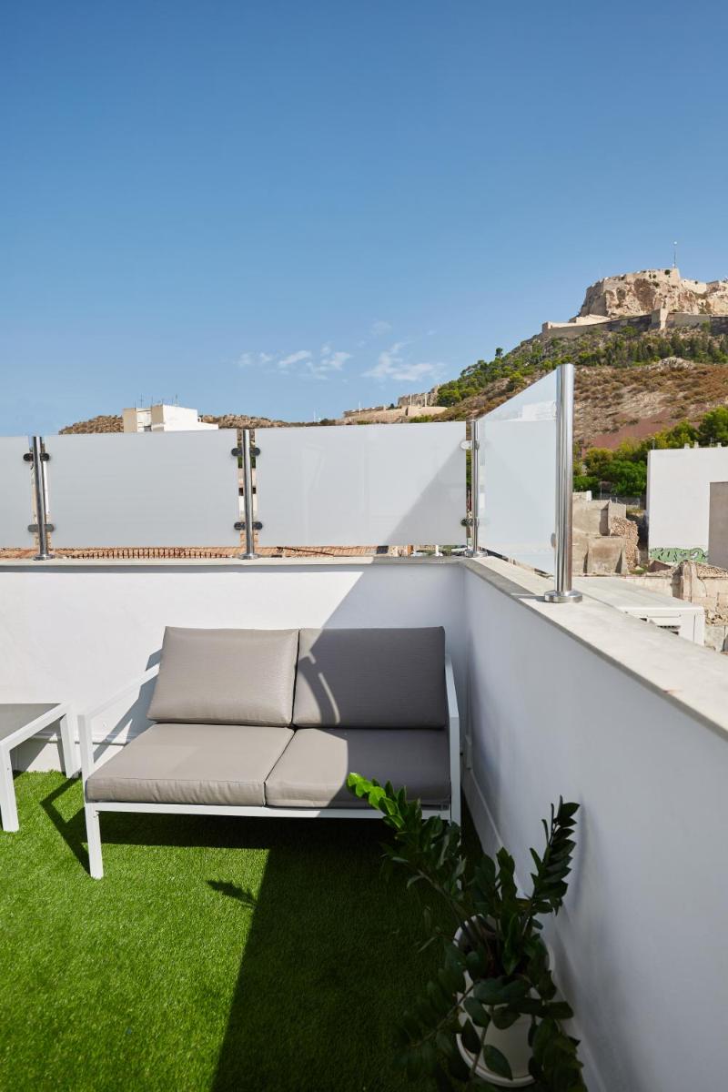 un sofá en un balcón con césped verde en Apart-hotel Happy Life, en Alicante