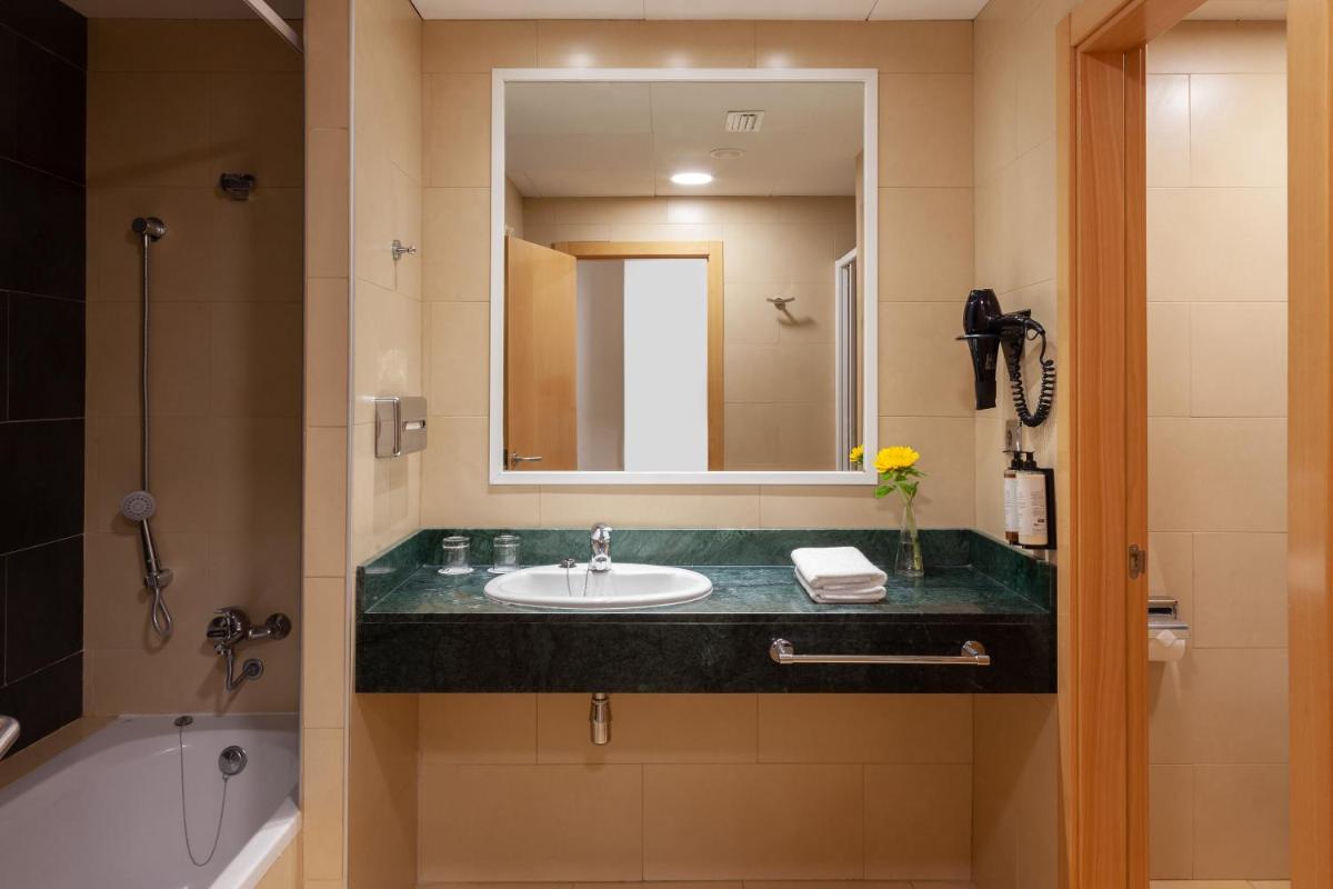 Un baño con lavabo, espejo y bañera. en Playamarina, en Isla Canela