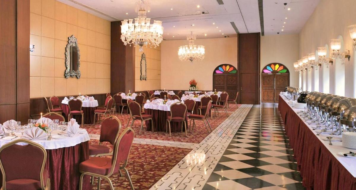 a banquet hall with tables and chairs and chandeliers at The Grand Imperial - Heritage Hotel in Agra