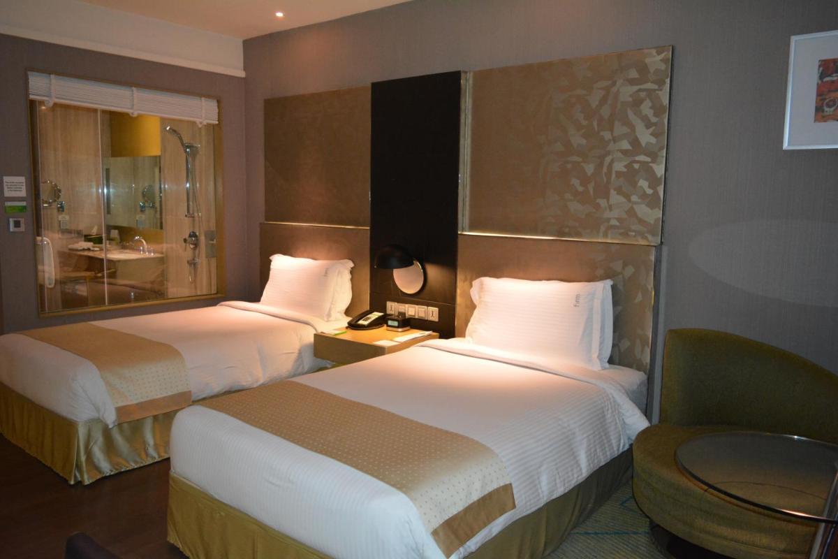 a hotel room with two beds and a chair at Holiday Inn New Delhi Aerocity by IHG in New Delhi
