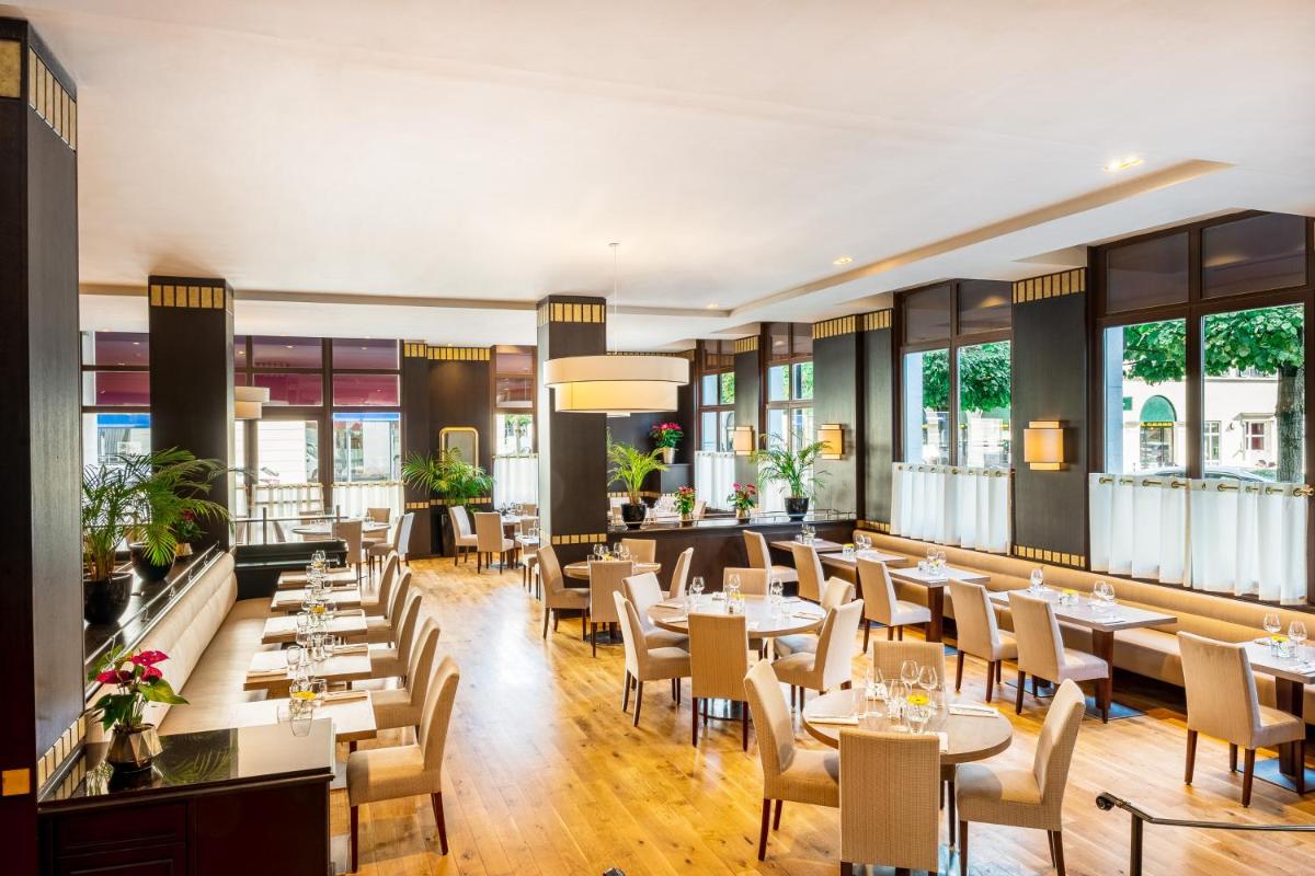 un restaurant avec des tables, des chaises et des fenêtres dans l'établissement Relais Spa Val d'Europe, à Chessy