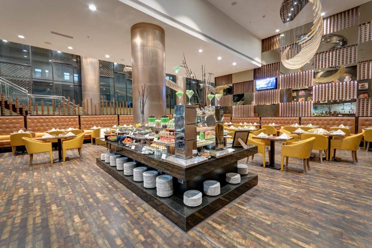 a restaurant with tables and chairs in a room at Holiday Inn Kolkata Airport by IHG in Kolkata