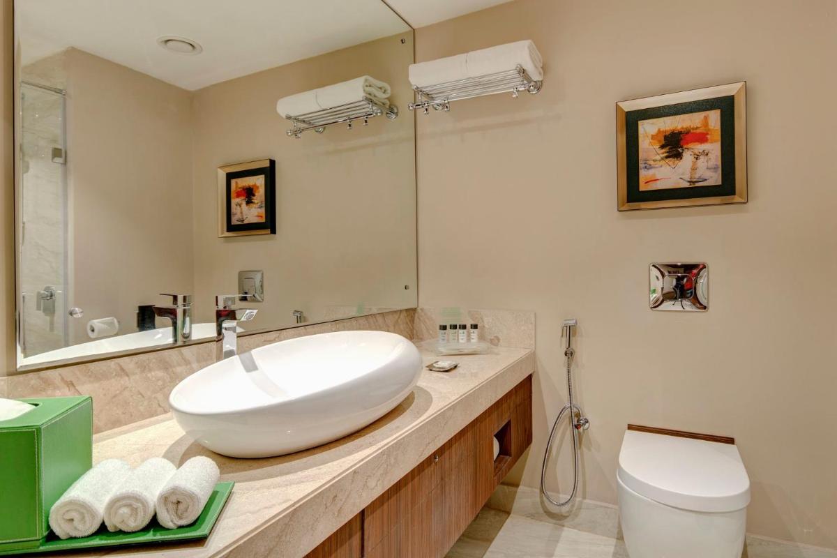 a bathroom with a white sink and a toilet at Holiday Inn Kolkata Airport by IHG in Kolkata