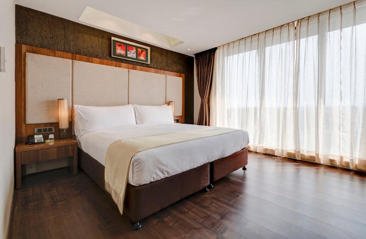 a bedroom with a large bed and a large window at Holiday Inn Kolkata Airport by IHG in Kolkata