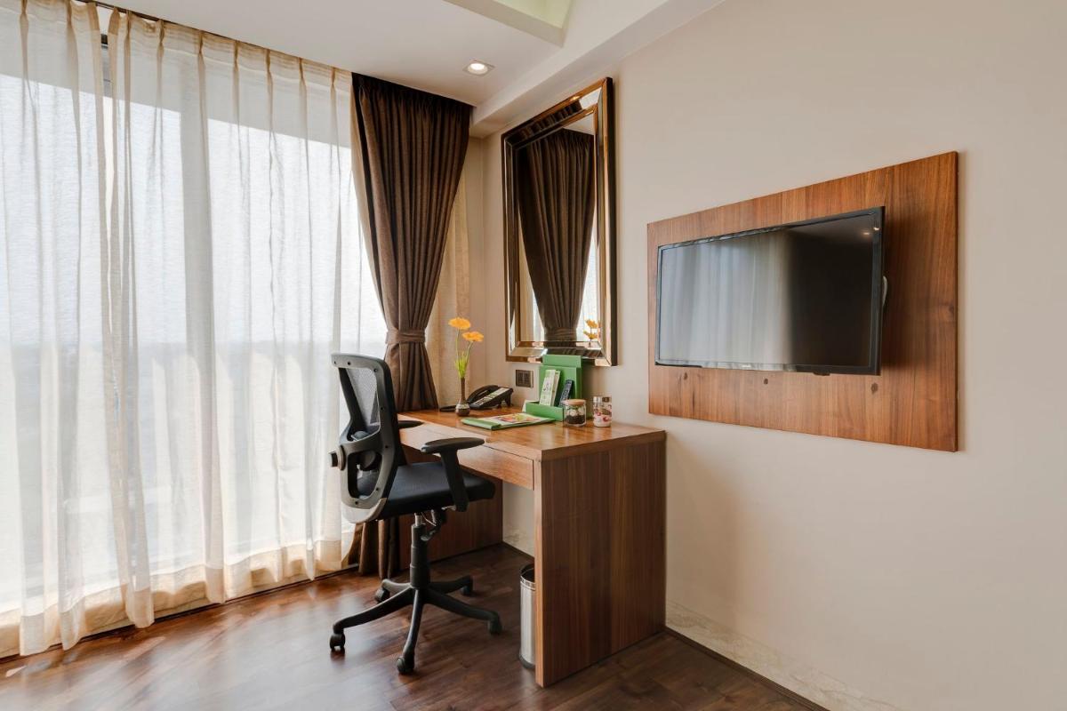 a room with a desk with a computer and a television at Holiday Inn Kolkata Airport by IHG in Kolkata