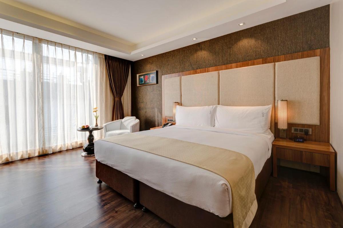 a hotel room with a large bed and a large window at Holiday Inn Kolkata Airport by IHG in Kolkata