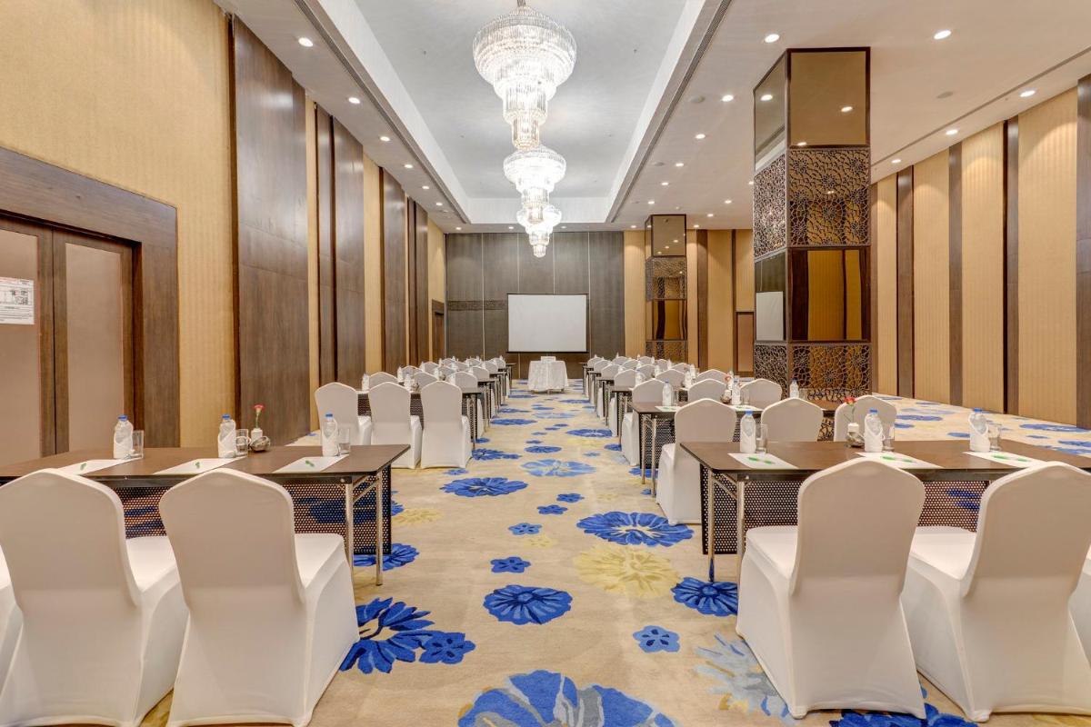 a conference room with tables and chairs and a podium at Holiday Inn Kolkata Airport by IHG in Kolkata
