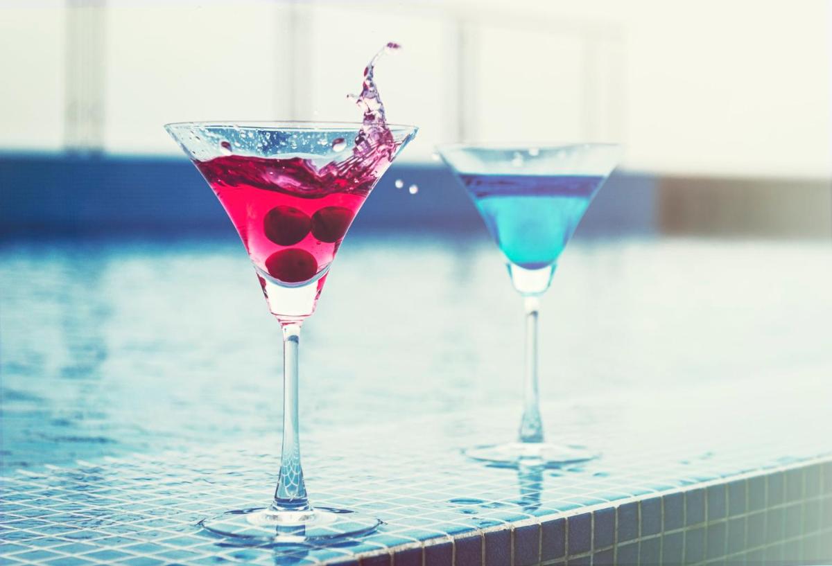two martini glasses sitting on a table next to a swimming pool at Holiday Inn Kolkata Airport by IHG in Kolkata