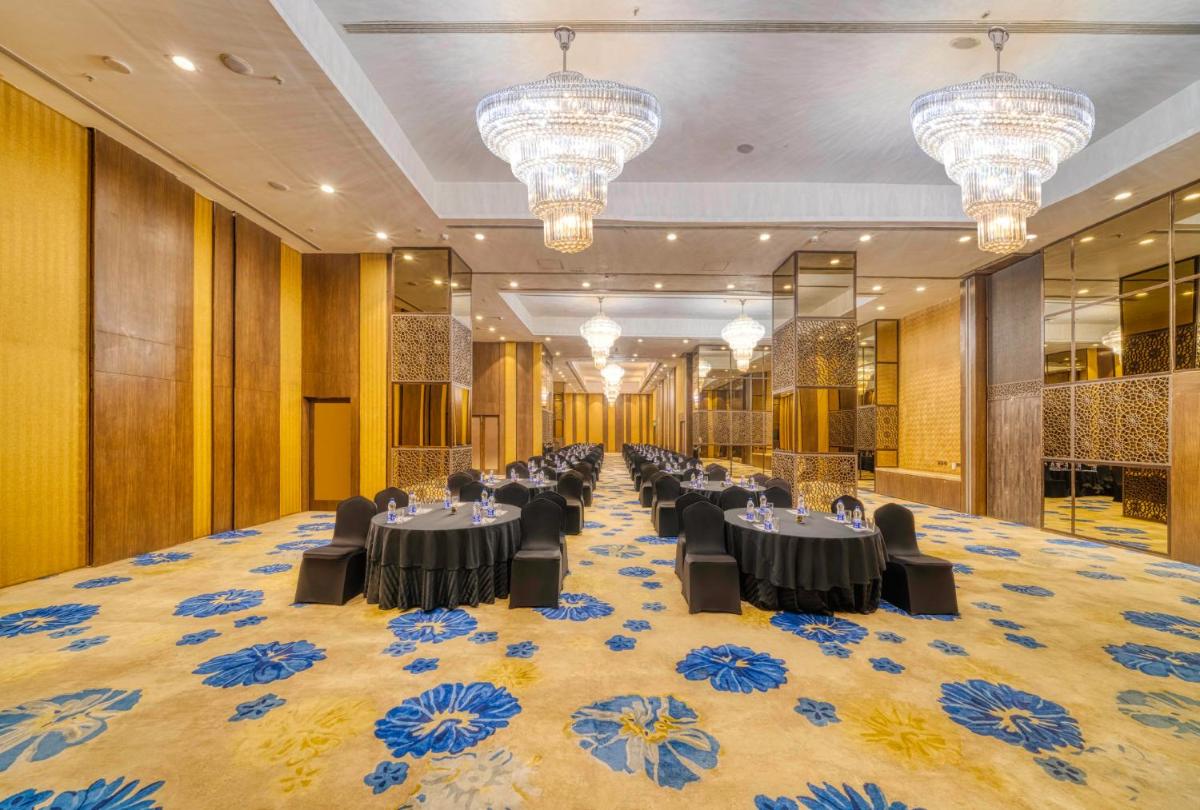 a banquet hall with black tables and chairs and chandeliers at Holiday Inn Kolkata Airport by IHG in Kolkata