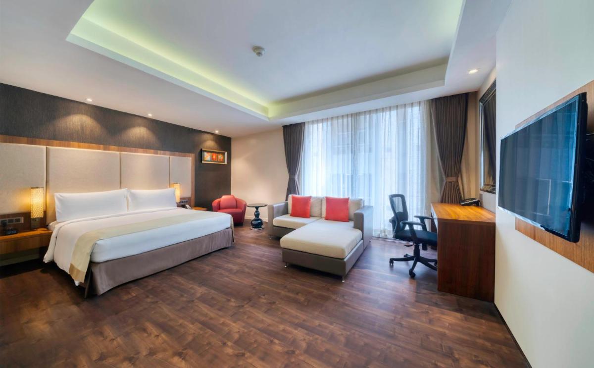 a hotel room with a bed and a chair and a television at Holiday Inn Kolkata Airport by IHG in Kolkata
