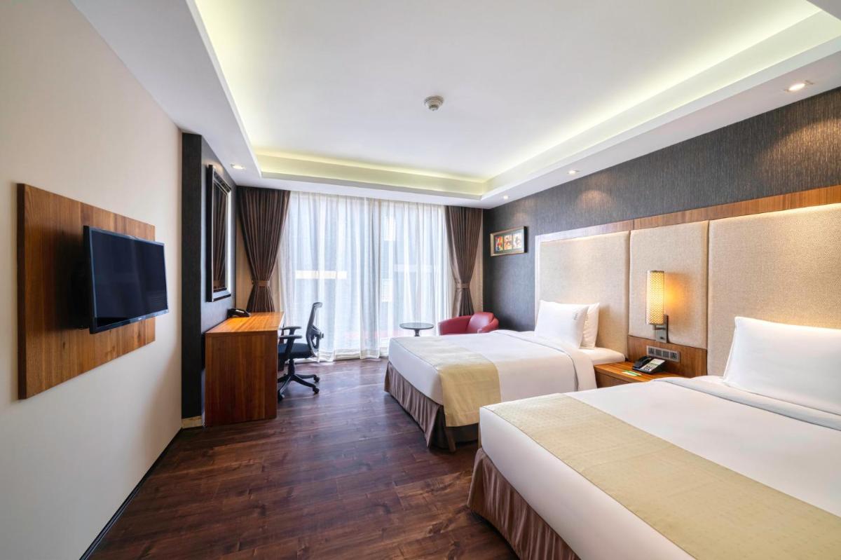 a hotel room with two beds and a television at Holiday Inn Kolkata Airport by IHG in Kolkata
