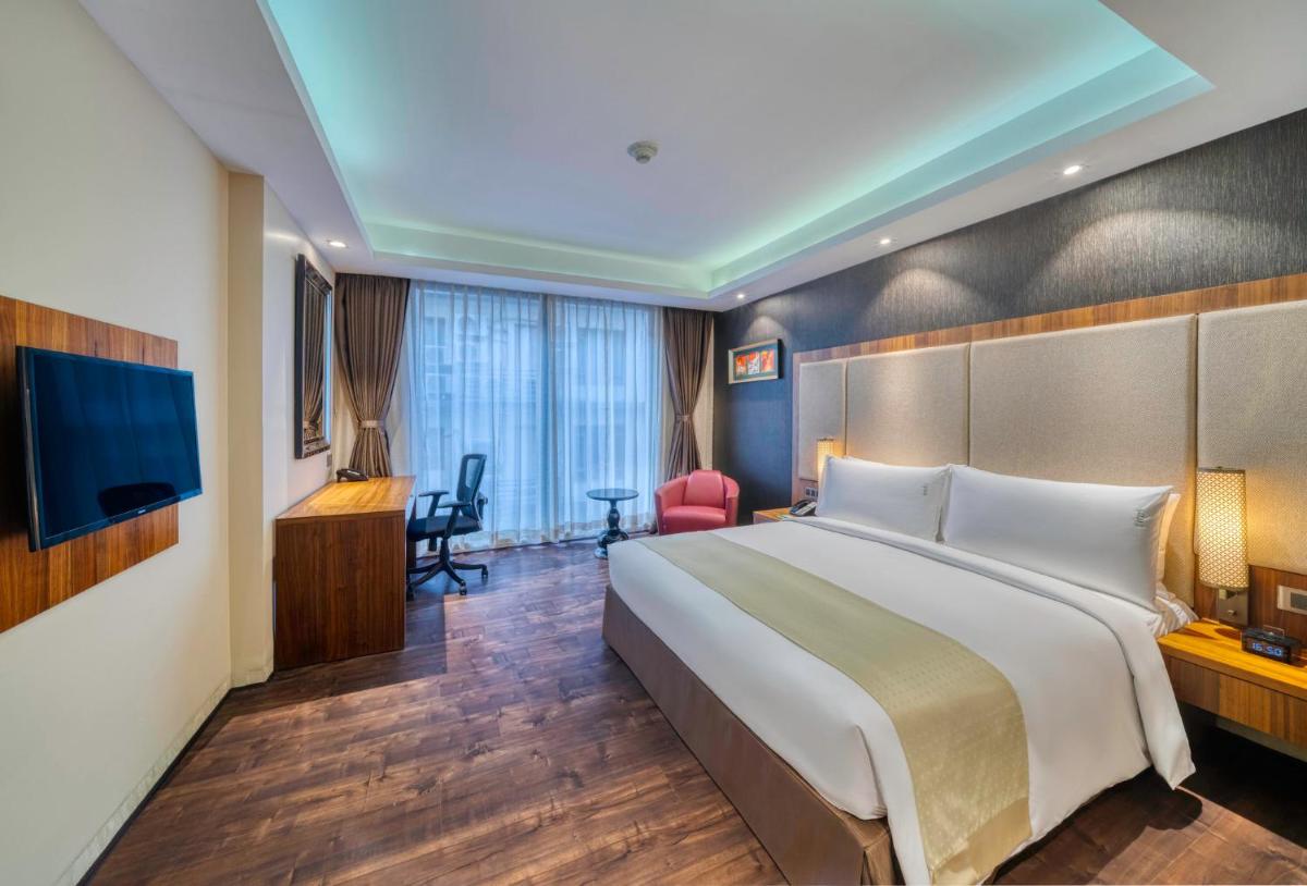 a hotel room with a large bed and a television at Holiday Inn Kolkata Airport by IHG in Kolkata