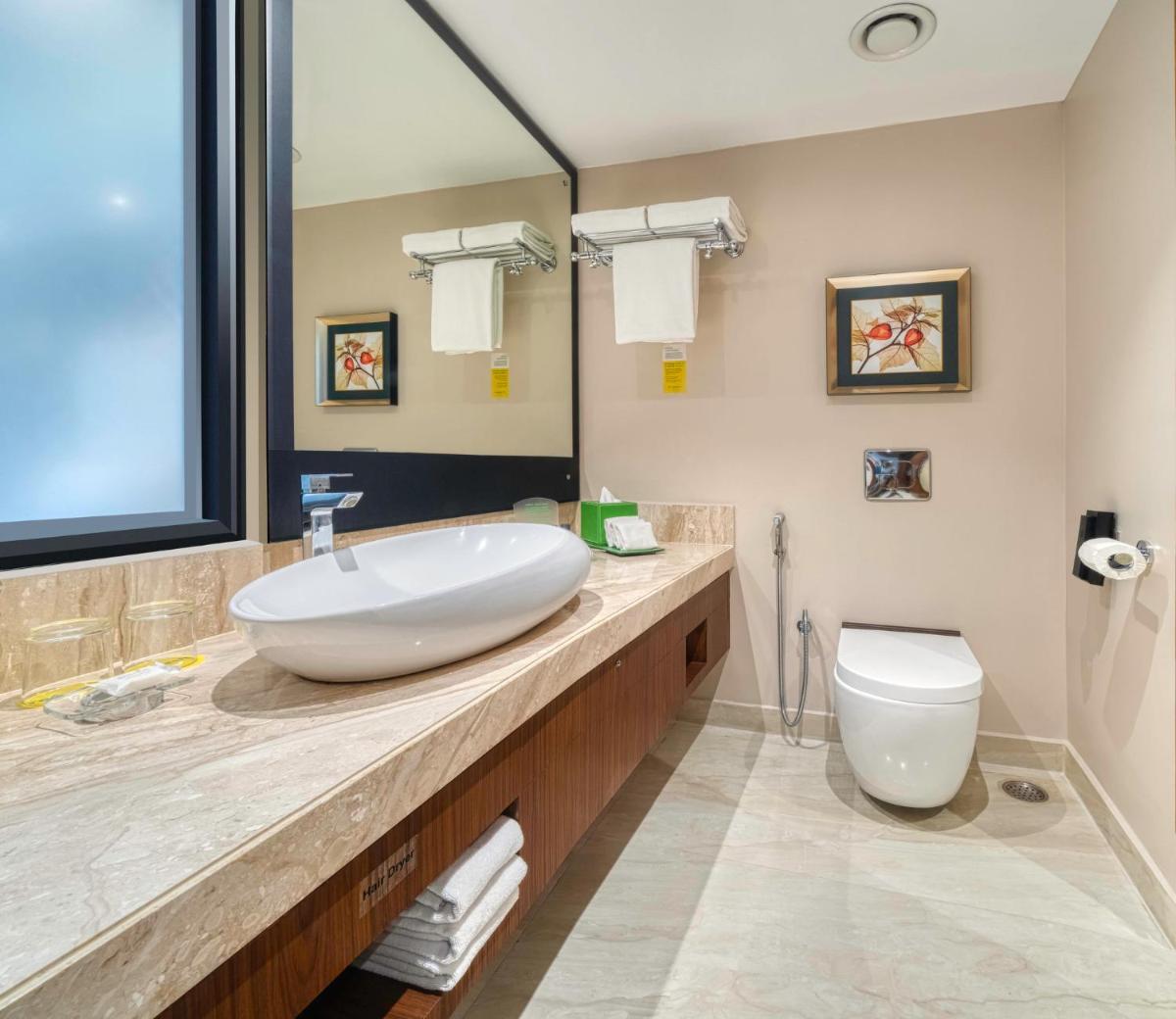 a bathroom with a sink and a toilet at Holiday Inn Kolkata Airport by IHG in Kolkata