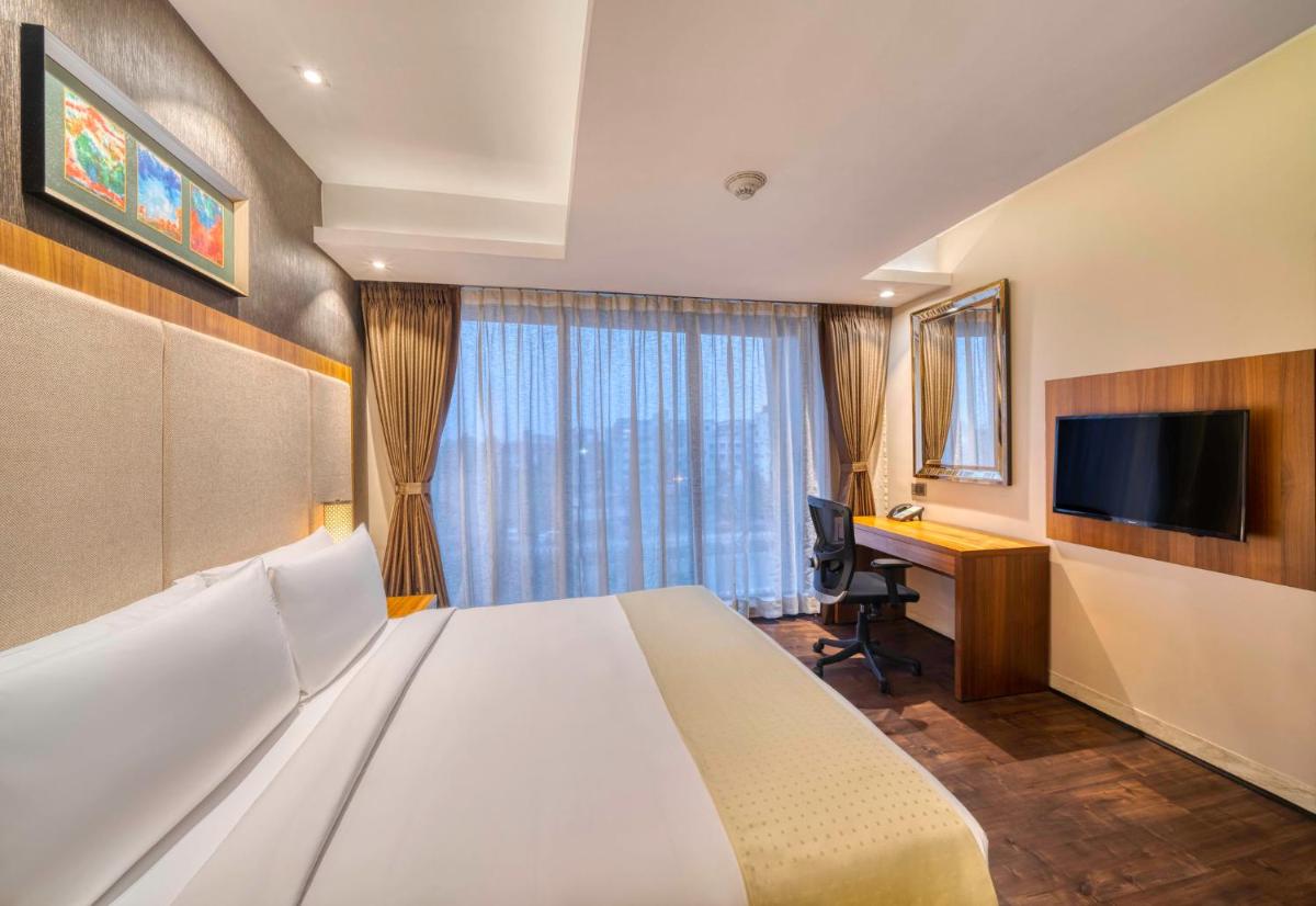 a hotel room with a bed and a desk and a television at Holiday Inn Kolkata Airport by IHG in Kolkata