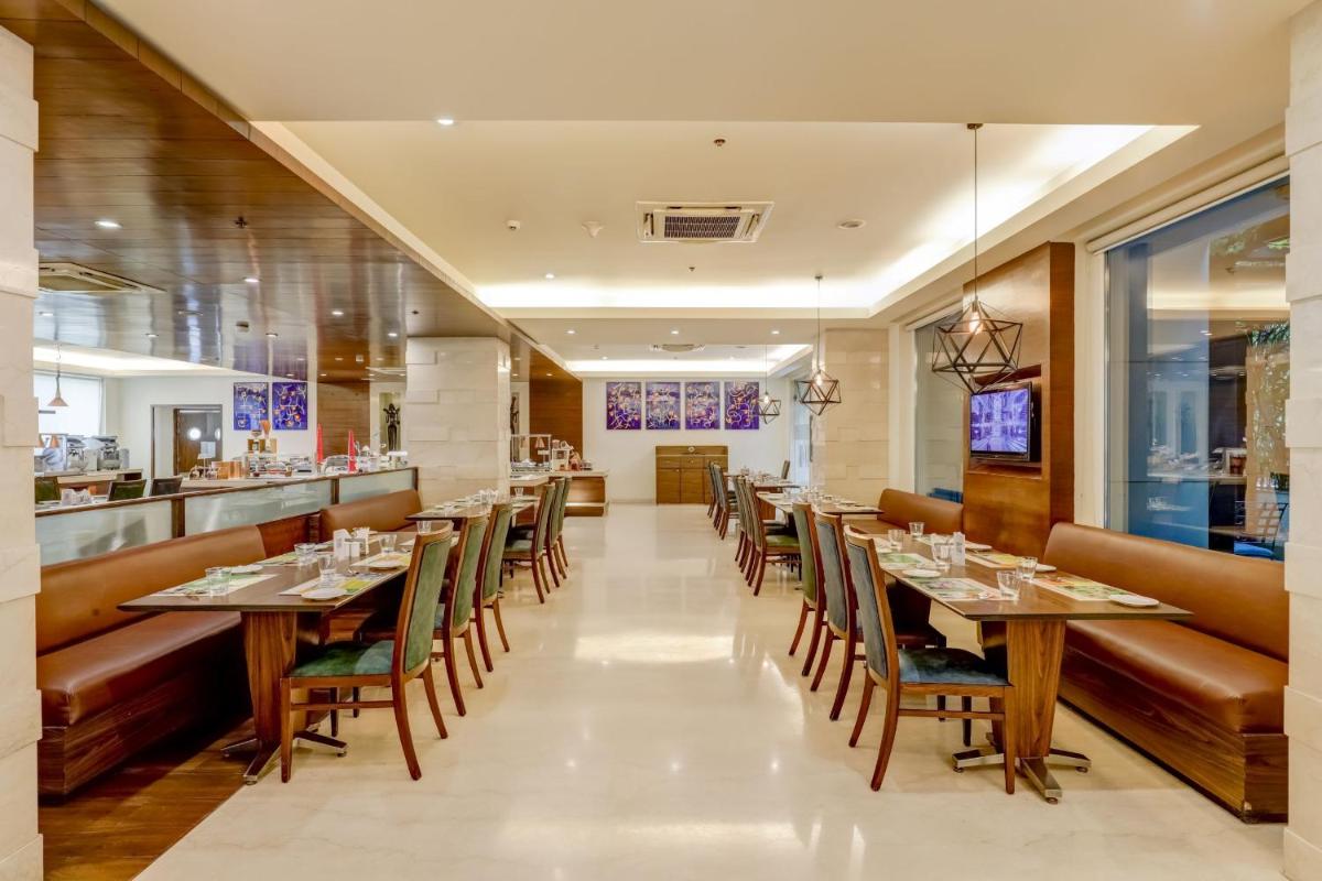 a restaurant with tables and chairs and a bar at Lemon Tree Premier, Delhi Airport in New Delhi a restaurant with tables and chairs and a bar at Lemon Tree Premier, Delhi Airport in New Delhi