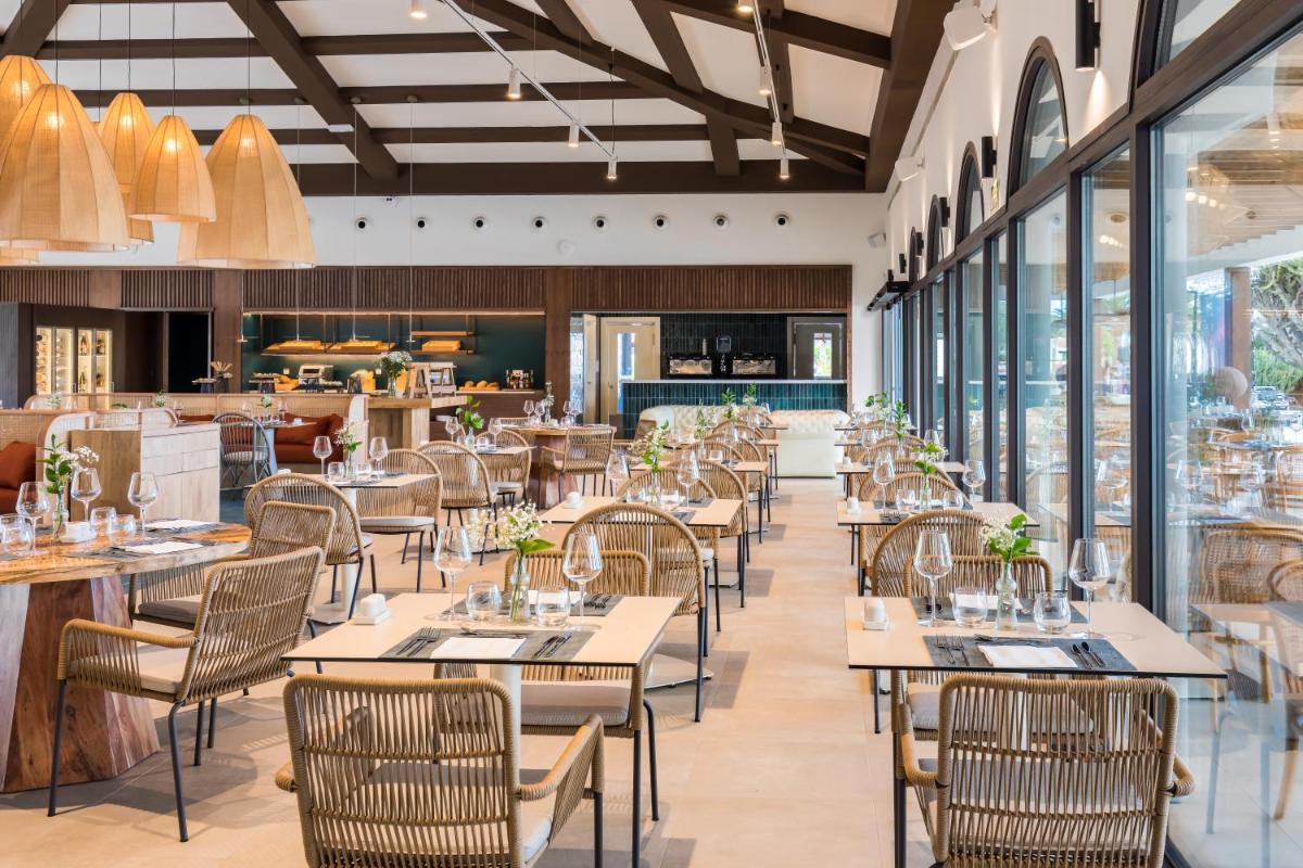 Un restaurante con mesas, sillas y ventanas. en Barceló Fuerteventura Royal Level - Adults Only, en Caleta de Fuste