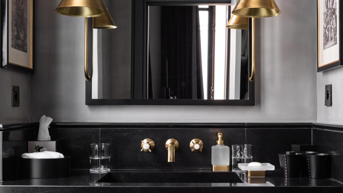 une salle de bain avec un lavabo noir et un miroir dans l'établissement Monsieur George Hotel & Spa - Champs-Elysées, à Paris