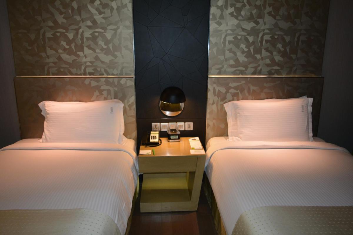 a hotel room with two beds and a table with a phone at Holiday Inn New Delhi Aerocity by IHG in New Delhi