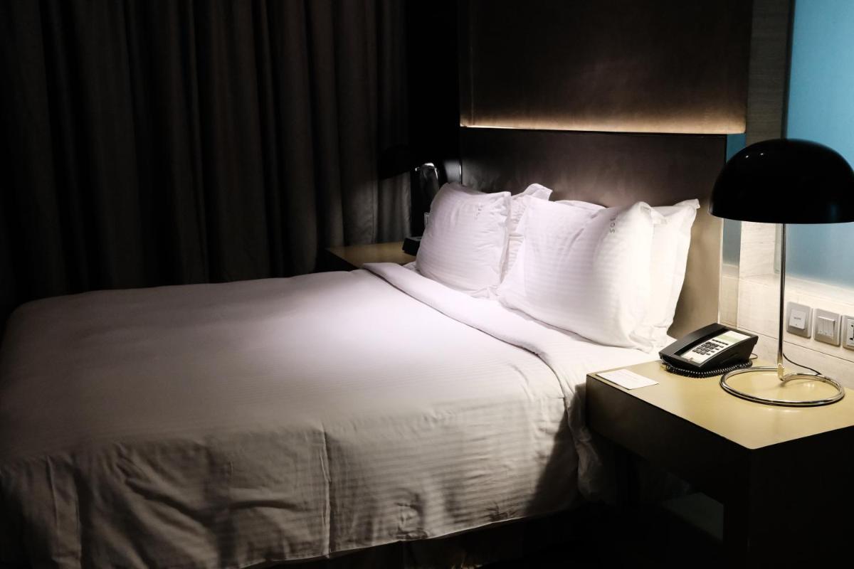 a bed in a hotel room with a phone on a table at Holiday Inn New Delhi Aerocity by IHG in New Delhi