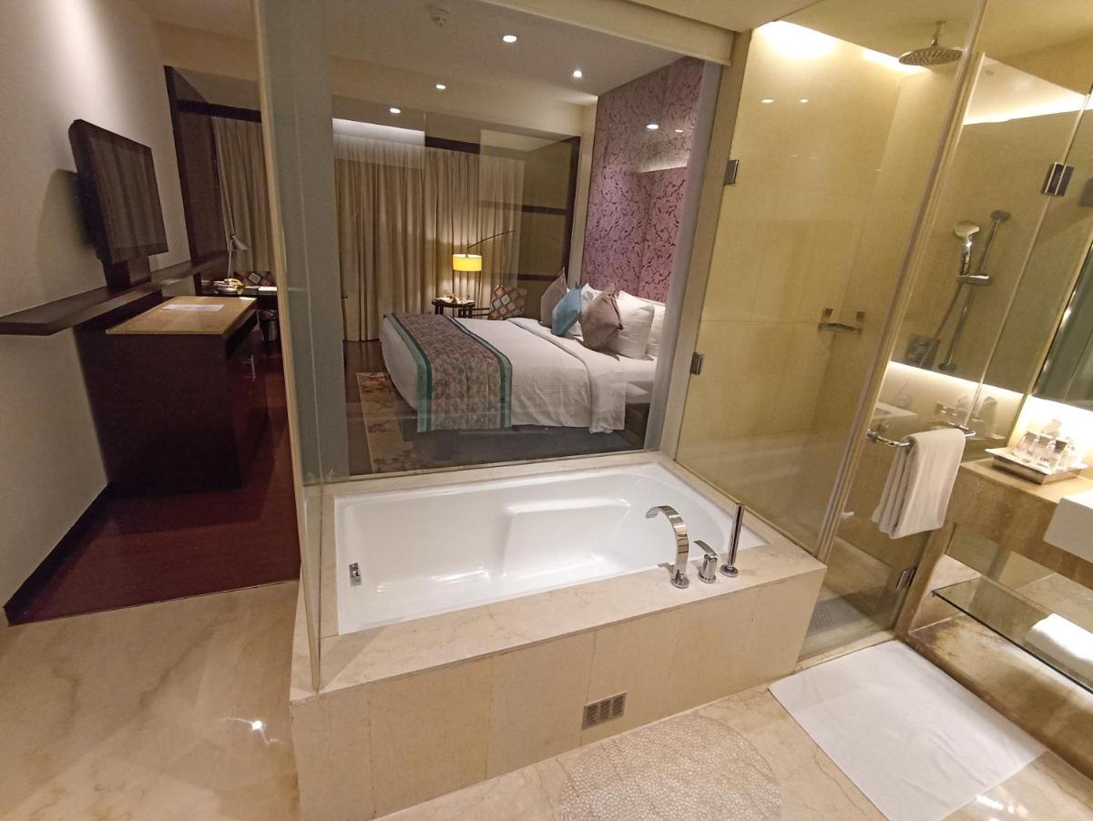 a bathroom with a bath tub and a bedroom at Hotel Royal Orchid Jaipur, Tonk Road in Jaipur