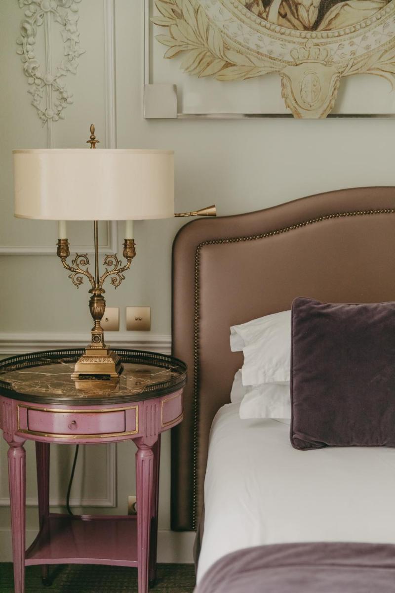 une table avec une lampe à côté d'un lit dans l'établissement La Maison Favart, à Paris