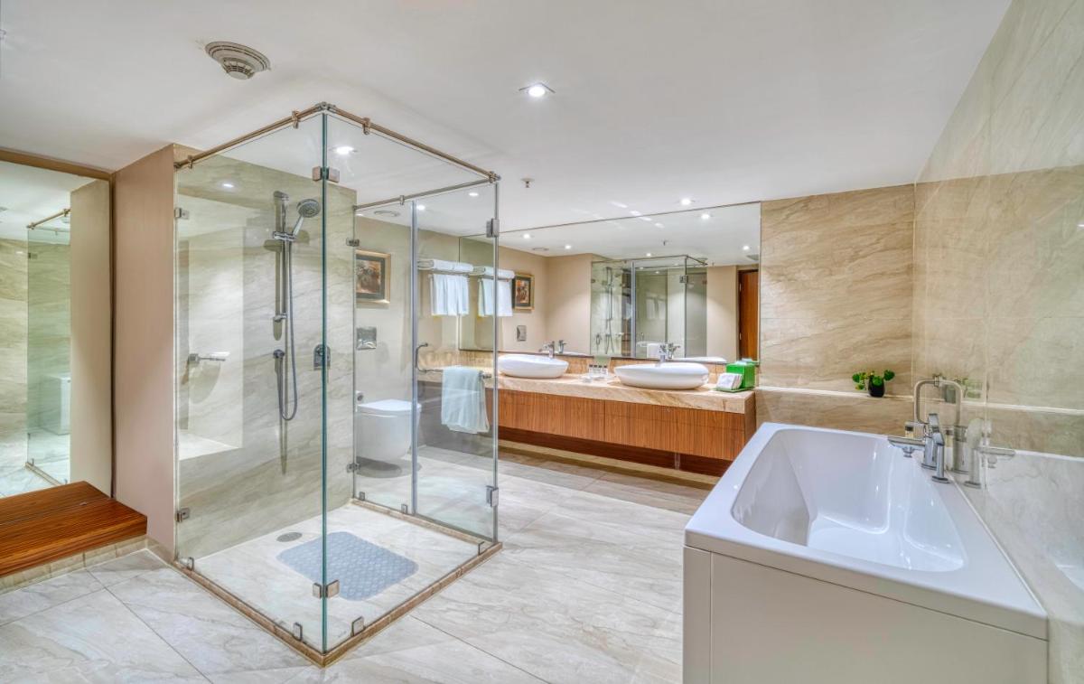 a bathroom with a glass shower and a sink at Holiday Inn Kolkata Airport by IHG in Kolkata