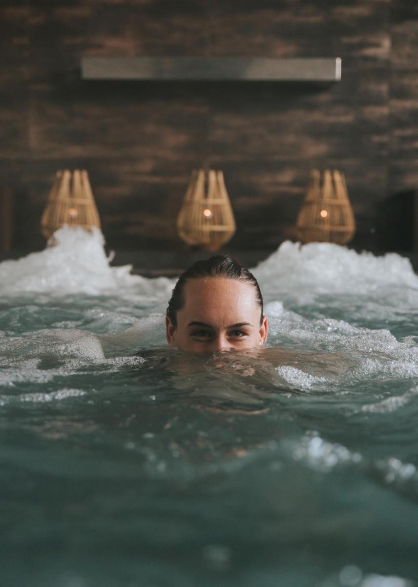 Una mujer está nadando en una bañera. en Park Hotel San Jorge & Spa by Escampa Hotels, en Platja d'Aro