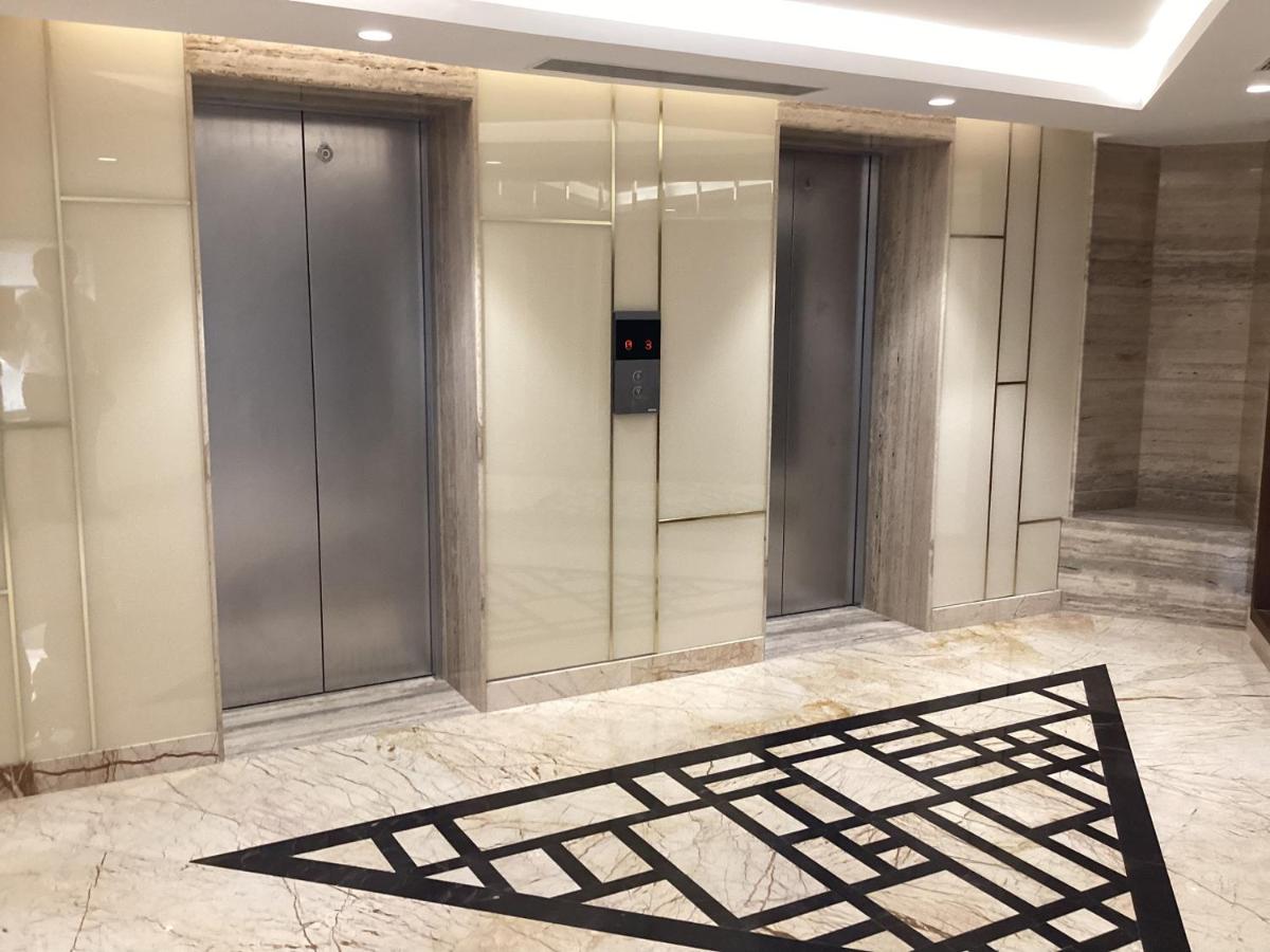a lobby with elevators and a black mat on the floor at Pharos Hotels in Chennai