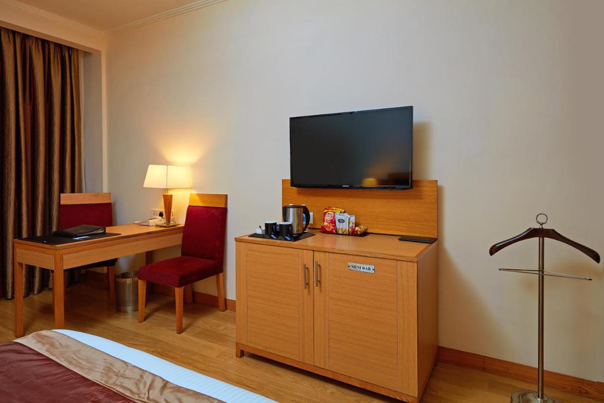 a hotel room with a bed and a desk with a television at Park Plaza Chennai OMR in Chennai