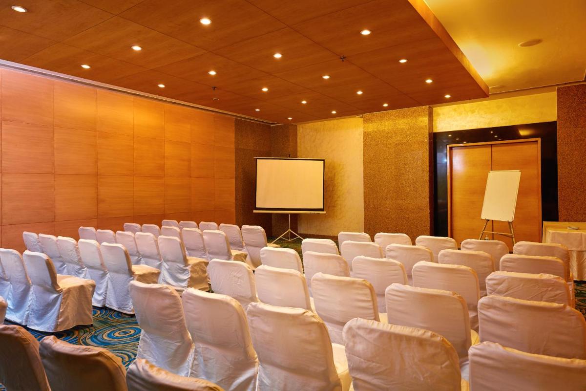 a conference room with white chairs and a screen at Park Plaza Chennai OMR in Chennai