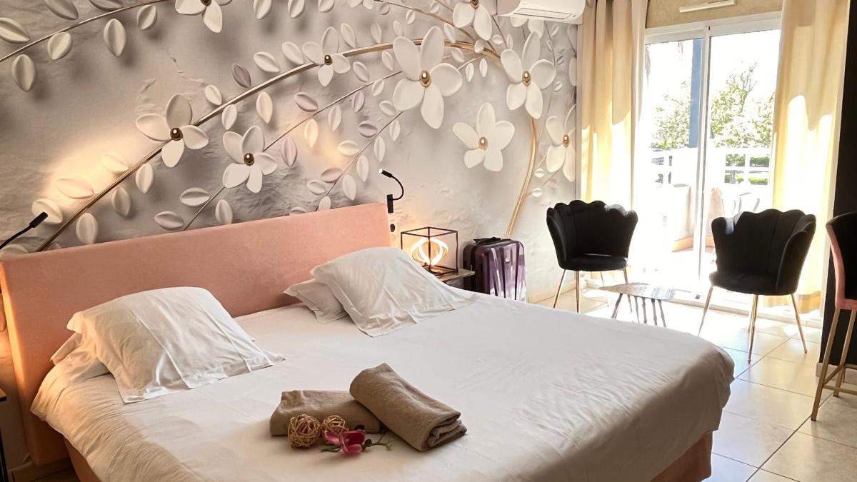 une chambre avec un lit orné de fleurs blanches au mur dans l'établissement Résidence Hôtelière Natureva & Spa, au Cap d'Agde