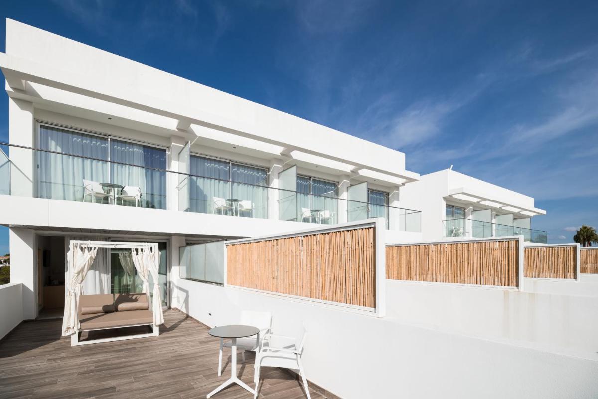 Casa blanca con balcón con mesa y sillas en Petit Sagitario Adults only, en Ciutadella