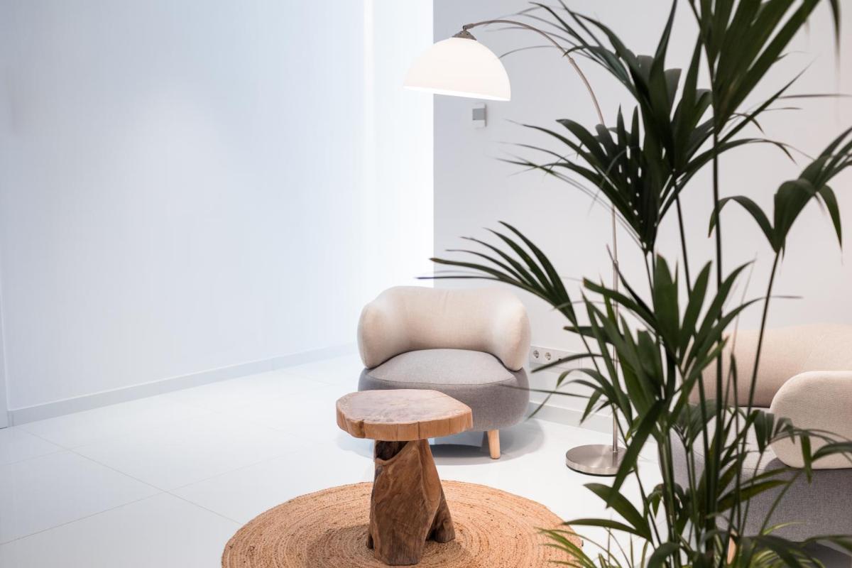 una silla y un taburete en una habitación con una planta en Petit Sagitario Adults only, en Ciutadella